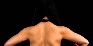 Imagen de una mujer de espaldas donde se aprecia su cabello y brazos.