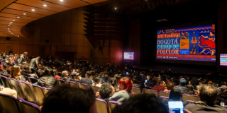 Imagen de un teatro donde se aprecia en la pantalla el aviso del Festival.