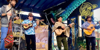 Imagen de cuatro (4) hombres vestidos con ropa típica campesina y tocan instrumentos musicales de cuerda.