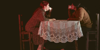 Imagen de las dos mujeres protagonistas de la obra de teatro sentadas a la mesa tomando alguna bebida.