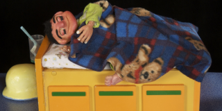 Imagen de un títere de un hombre sobre una cama