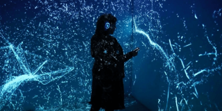Imagen de una mujer con audifonos en un espacio oscuro con luces en un evento en Bogotá.