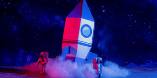 Imagen de cohete en cartón con dos astronautas en escena 