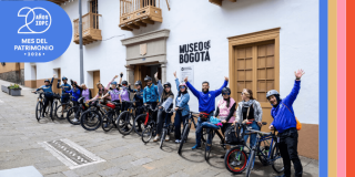 Imagen de personas en bicicletas al frente del Museo de Bogotá con logos del IDPC