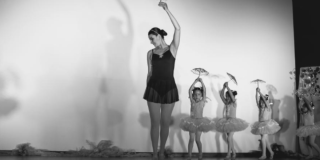 Imagen de una mujer vestida de traje negro de ballet y cuatro niñas vestidas de ballet con una pequeña sombrilla en sus manos.