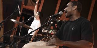 Imagen de un hombre cantando y el otro hombre tocando los tambores 