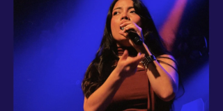 Imagen de una mujer joven que canta con un micrófono en su mano.
