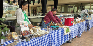 Imagen de varias personas que ofrecen en sus stand los productos de mercado campesino.