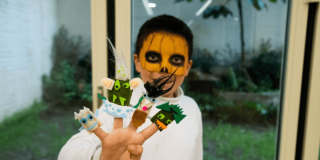 Imagen de niño con antifaz y títeres en la mano