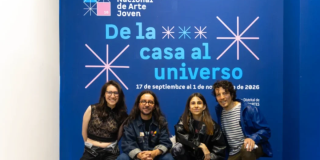 Imagen de dos hombres y dos mujeres que son los expositores de ´De la casa al universo` atras de ellos se ve el cartel promocional de la exposición.
