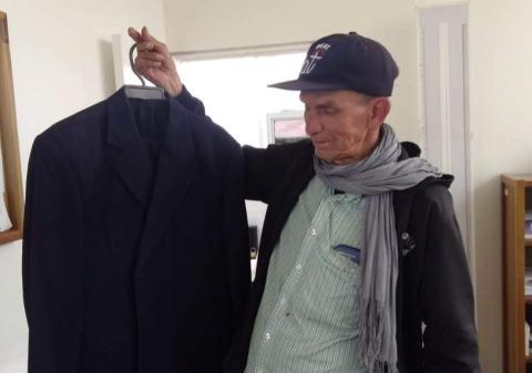 Un hombre mayor sostiene una chaqueta negra donada.