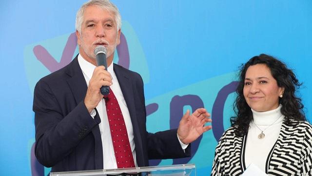 Primer plano del Alcalde Enrique Peñalosa hablando por micrófono, al lado de él esta la secretaria de Educación Claudia Puentes