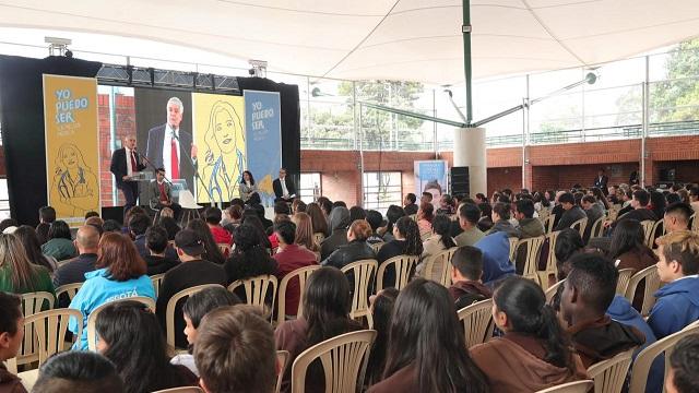 El Alcalde Enrique Peñalosa dando un conferencia frente a muchas personas sentadas enfrente de él 