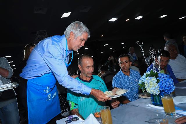 El Alcalde Enrique Peñalosa con un delantal sirviendo un plato de comida a una persona ex habitante de calle 
