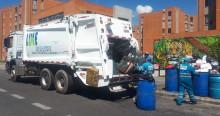 Foto de un camión recolector de basuras y operarios de aseo de LIME en Bogotá.