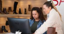 Foto de dos mujeres revisando una computadora en un negocio de calzado en Bogotá.