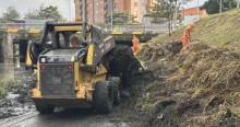 Foto que muestra un carro recolector y personas levantando residuos en un canal