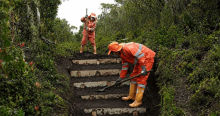 Foto que muestra dos personas con el uniforme de aguas de Bogotá instalando contrahuellas en un sendero ecológico