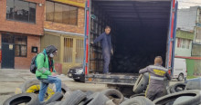 Foto que muestra personas recolectando llantas y colocandolas en un camión 
