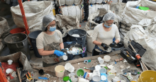 Foto que muesta dos personas con tapabocas y guantes separando residuos