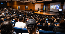 Imagen de varias personas en un auditorio escuchando conversatorio.