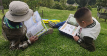 Imagen de dos niños leyendo libros en césped 