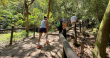 Personas ascienden sendero de Monserrate entre árboles, barandas de madera y camino empedrado