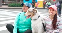 Imagen de dos mujeres sentadas al lado de su perro blanco con café claro.