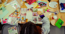 Imagen de una niña sentada trabajando en una mesa un collage.