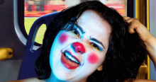 Imagen de una mujer joven que tiene su cara pintada como una payasa.
