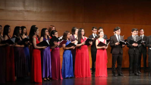 Un grupo de jóvenes vestidos formalmente cantan.