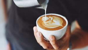 Un hombre preparar un café con un detalle de arte latte.