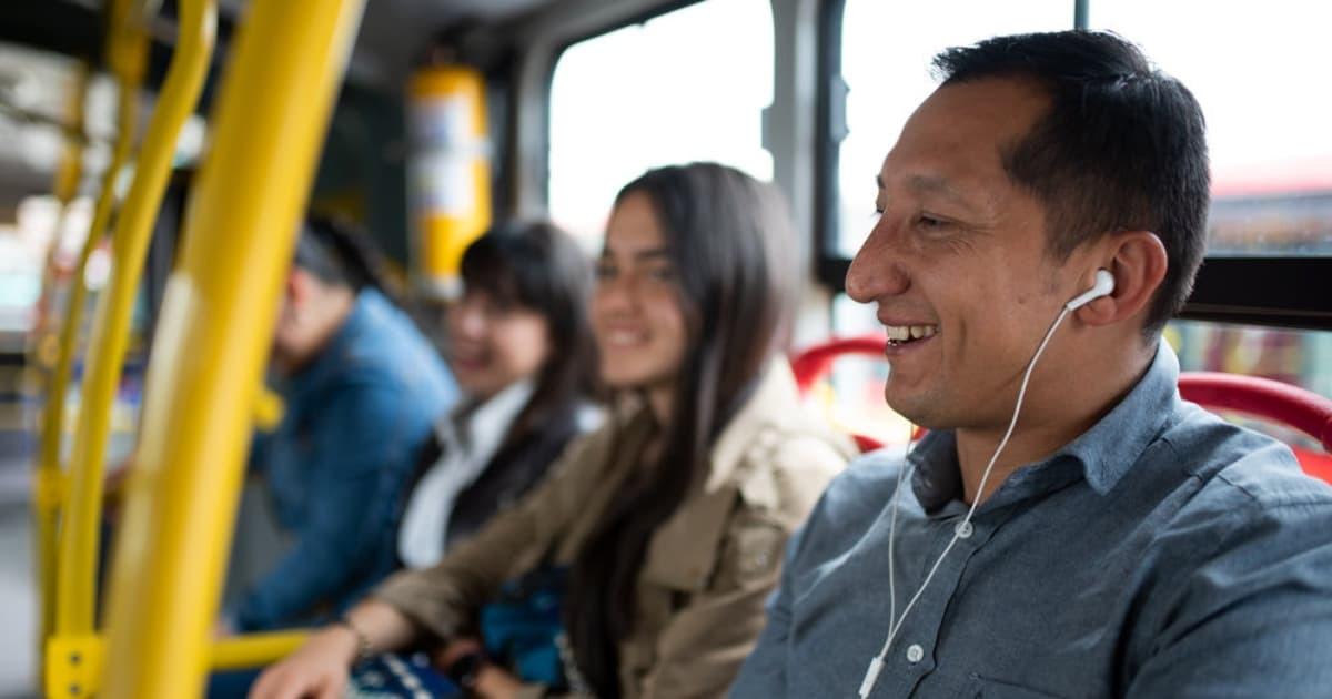 Foto de un hombre en un bus de TransMilenio usando audífonos.