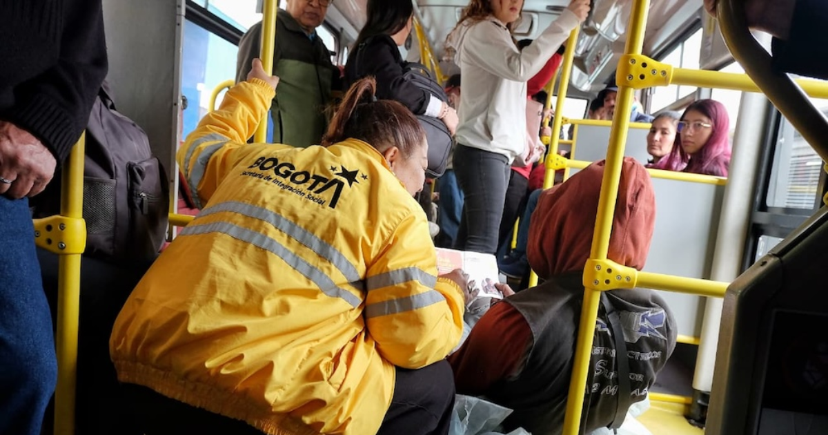 Imagen de una funcionaria atendiendo a un habitante de calle en un bus de TransMilenio
