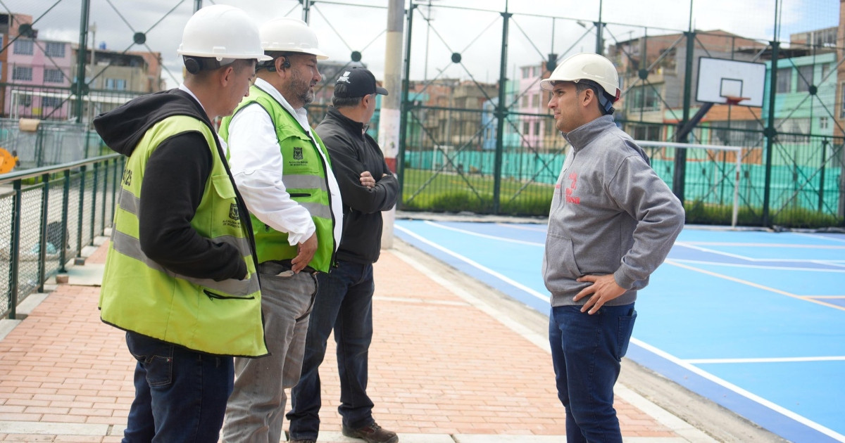 Foto que muestra cuatro personas con casco blanco hablando en un parque