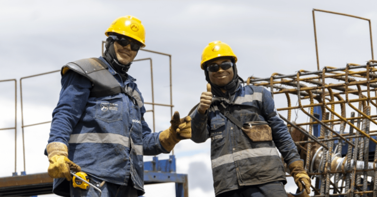 Imagen de dos trabajadores de la obra del Metro de Bogotá vestidos con su uniforme.