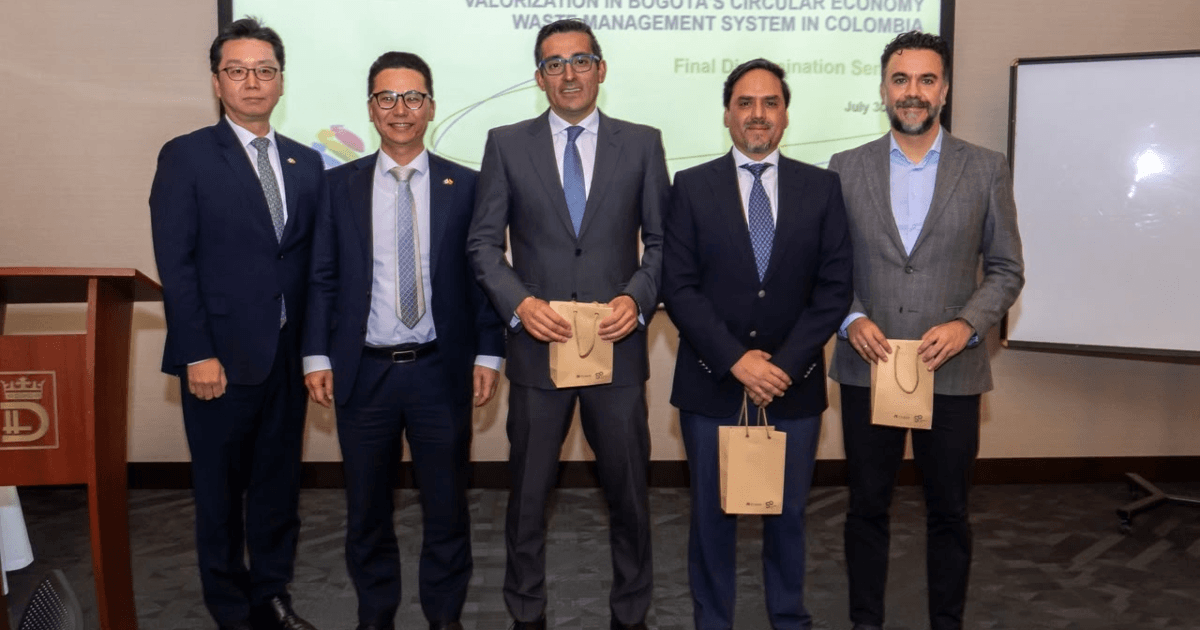 Foto que muestra cinco hombres en un auditorio sonriendo 