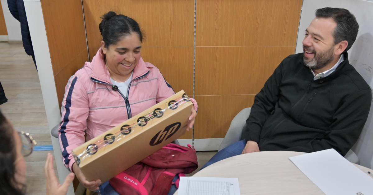 Imagen del alcalde Galán sonriendo junto a una señora quien recibió un computador