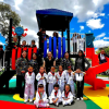 Foto de un grupo de niños y adultos disfruta un colorido parque infantil recién renovado bajo un cielo despejado