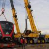Foto de una grua telescópica descargando uno de los vagones del tercer tren de la Línea 1 del Metro.