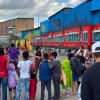 Foto de un grupo de niños y vecinos observando un mural colorido del Tren de la Sabana durante una actividad comunitaria en Los Mártires.