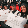 Imagen de estudiantes alzando sus diplomas de grado