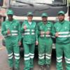 Foto de un grupo de operarios y operarias de aseo en Bogotá, al lado un camión recolector de basuras.