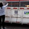 Foto que muestra un ecopunto y una ciudadana colocando residuos