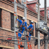 Imagen de técnicos de Enel colgados en postes de luz