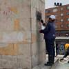 Foto que muestra un monumento de la ciudad y tres personas limpiandolo