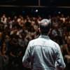 Foto de un hombre realizando una presentación ante un público en un audotorio.