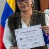 Mujer posando con un certificado de un programa de la Secretaría de la Mujer