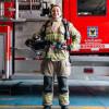 Mujer Bombera frente a un camión de bomberos.