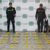 Uniformados y perro anitinarcótico frente a droga incautada en el aeropuerto El Dorado.